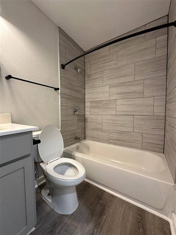 5018 San Jacinto Street, #107, Dallas, TX 75206 Bathroom featuring a built-in tub with a tile surround, coordinating wood-finish flooring, a white vanity countertop, and dark-finish fixtures