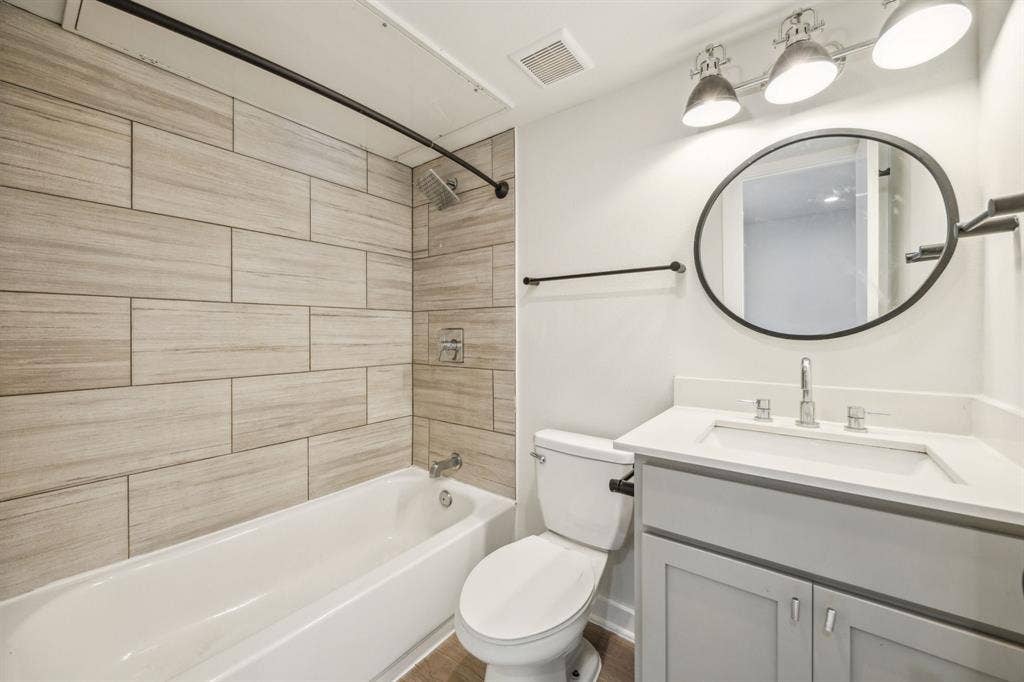 5018 San Jacinto Street, #107, Dallas, TX 75206 Bathroom featuring a white tub, wood-finish tile surround, and a rain showerhead