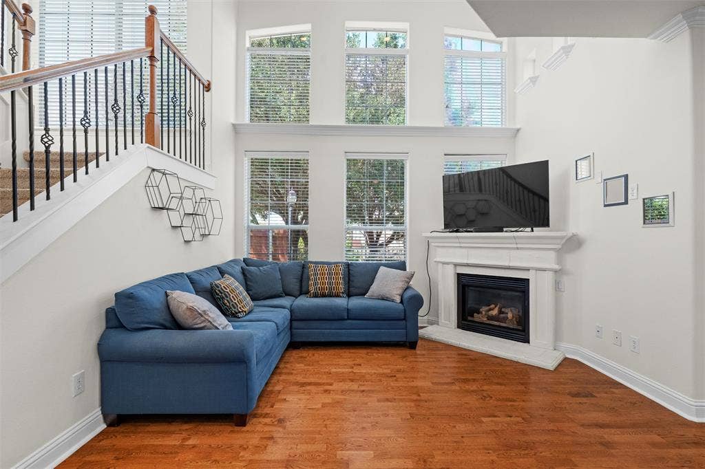 4424 Honfleur Court, Irving, TX 75038 Comfy living area with a towering ceiling, wood finished floors, a glass covered fireplace, and stairway