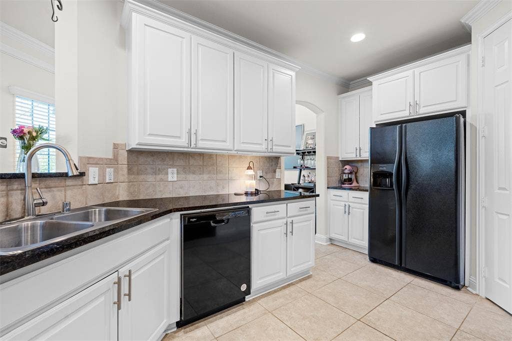 4424 Honfleur Court, Irving, TX 75038 Kitchen featuring black appliances, white cabinets, crown molding, tasteful backsplash, and light tile patterned flooring. So much cabinet space!!