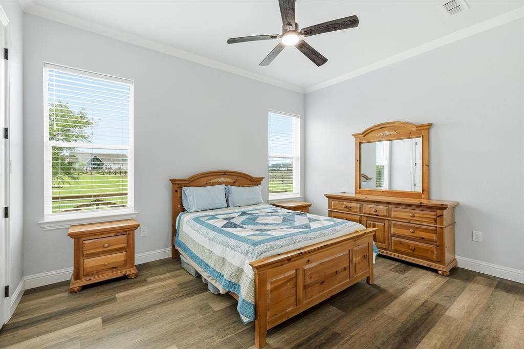 Guest Home - Spacious room featuring wood-finish flooring, two large windows with blinds, and a ceiling fan