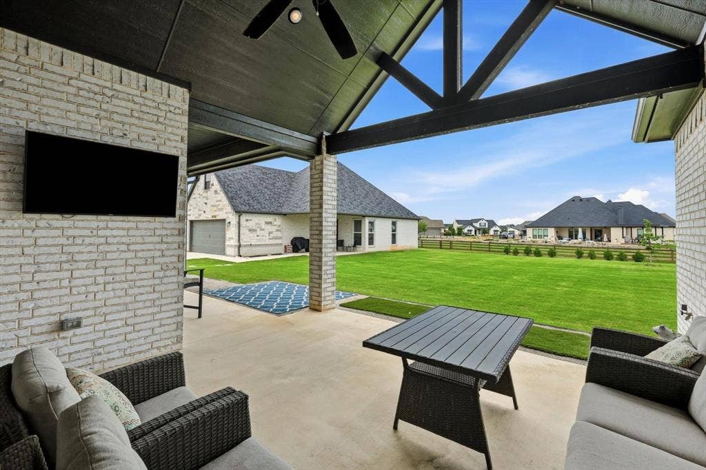 Covered patio featuring a slatted ceiling, exposed beam structure, and a ceiling fan