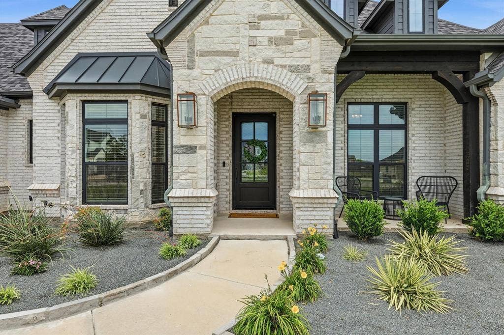 Main Home - Stone and brick exterior with dark trim accents and a black front door