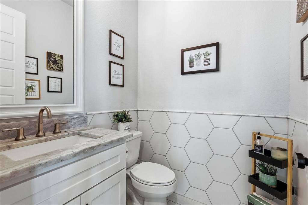 Jack & Jill bathroom featuring a white vanity with a stone countertop, an undermount sink, and a bronze-finish faucet