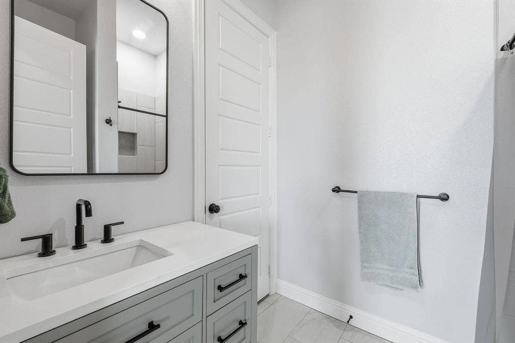 Guest Home (1 of 2 bathrooms) - Bathroom vanity featuring a white rectangular undermount sink, matte black faucet, and light gray cabinetry with black hardware