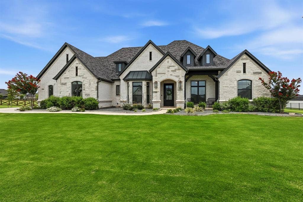 Main Home - Contemporary stone and brick exterior featuring a multi-gabled roofline, dark trim accents, varied window designs, and a black front door