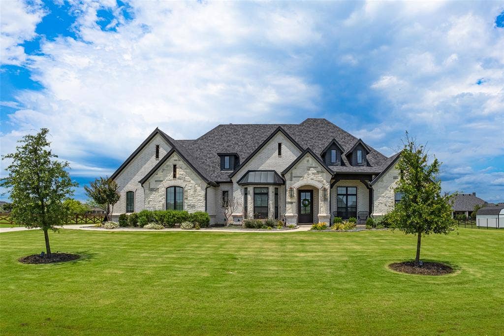 Main Home - Contemporary stone and brick exterior featuring a multi-gabled roofline, dark trim accents, varied window designs, and a black front door