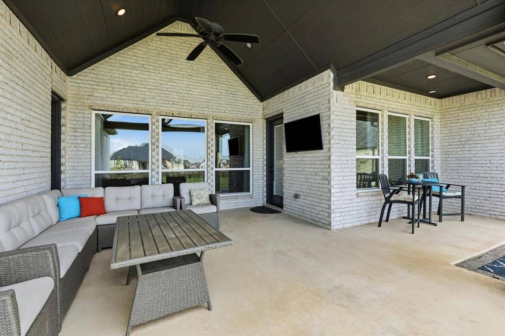 Covered patio featuring white brick exterior walls and a dark vaulted ceiling