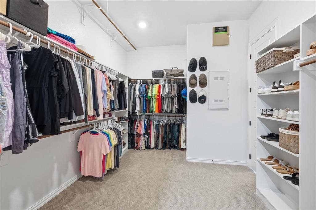 Spacious walk-in closet featuring light-colored carpeting, white walls, and recessed lighting