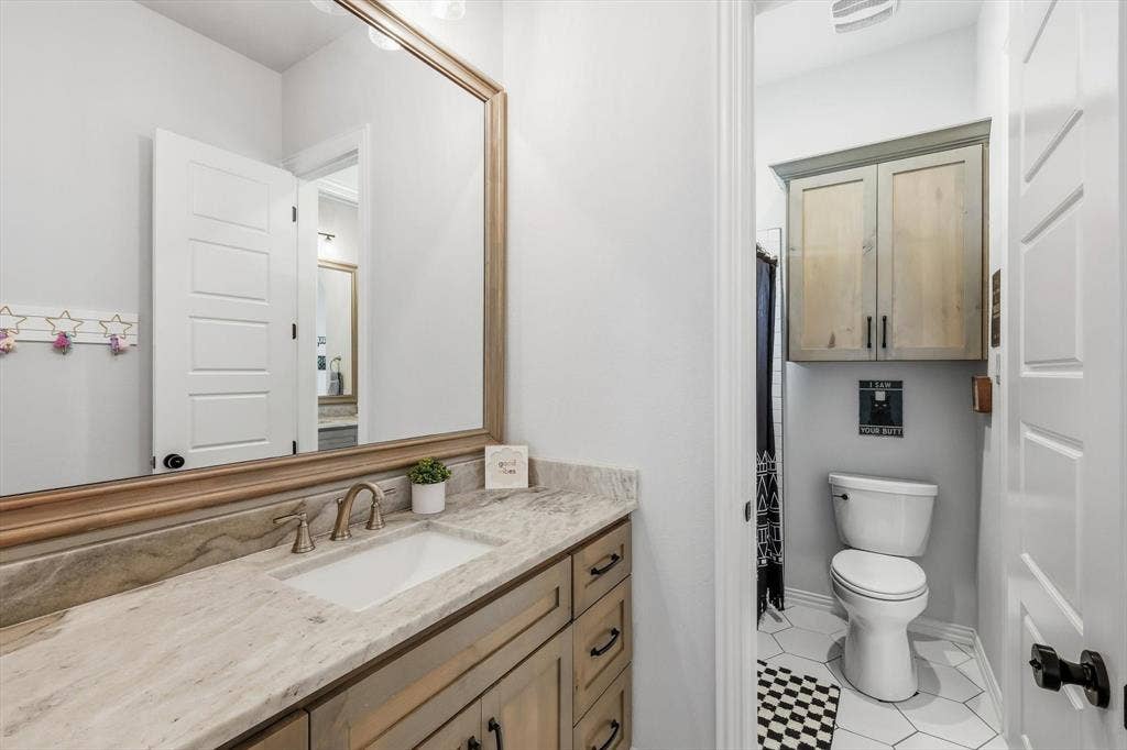 Jack & Jill bathroom vanity featuring a rectangular undermount sink, stone countertop, and brushed nickel faucet