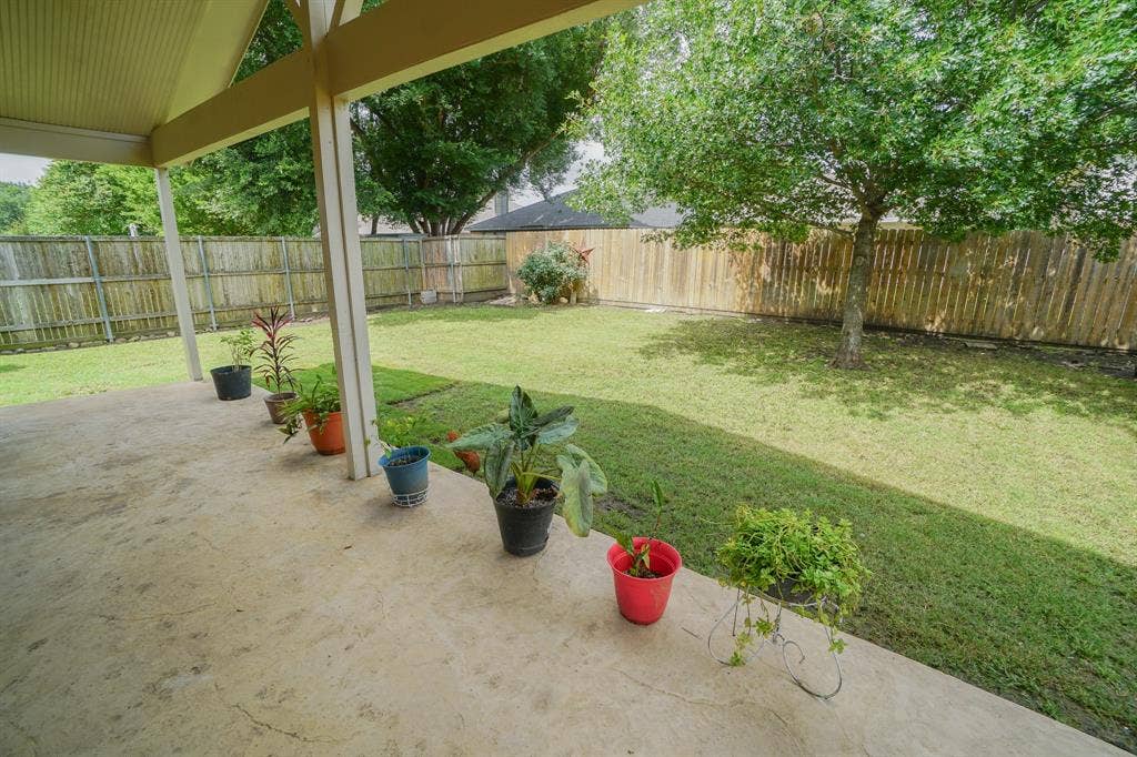203 Grassy Creek Drive, Wylie, TX 75098 Expansive backyard featuring a covered concrete patio, mature tree, and full perimeter wood fencing