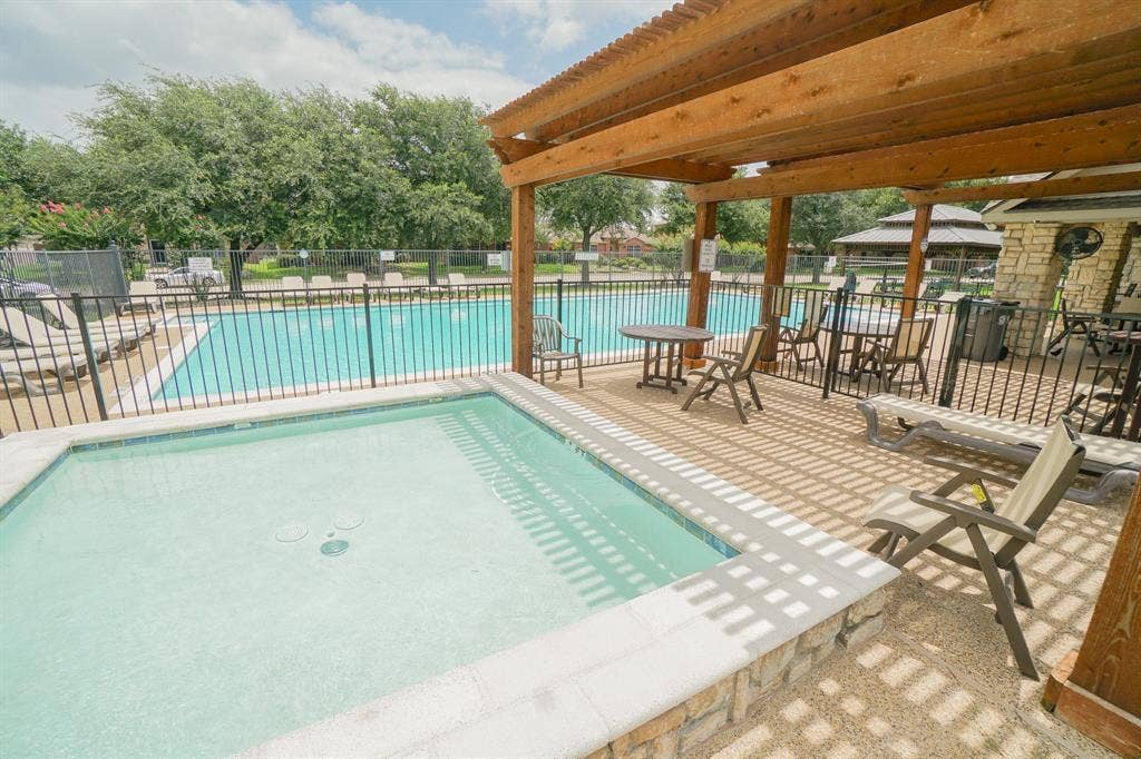 203 Grassy Creek Drive, Wylie, TX 75098 Community Pool and spa with a surrounding patio featuring a pergola, stone accents, and a nearby swimming pool