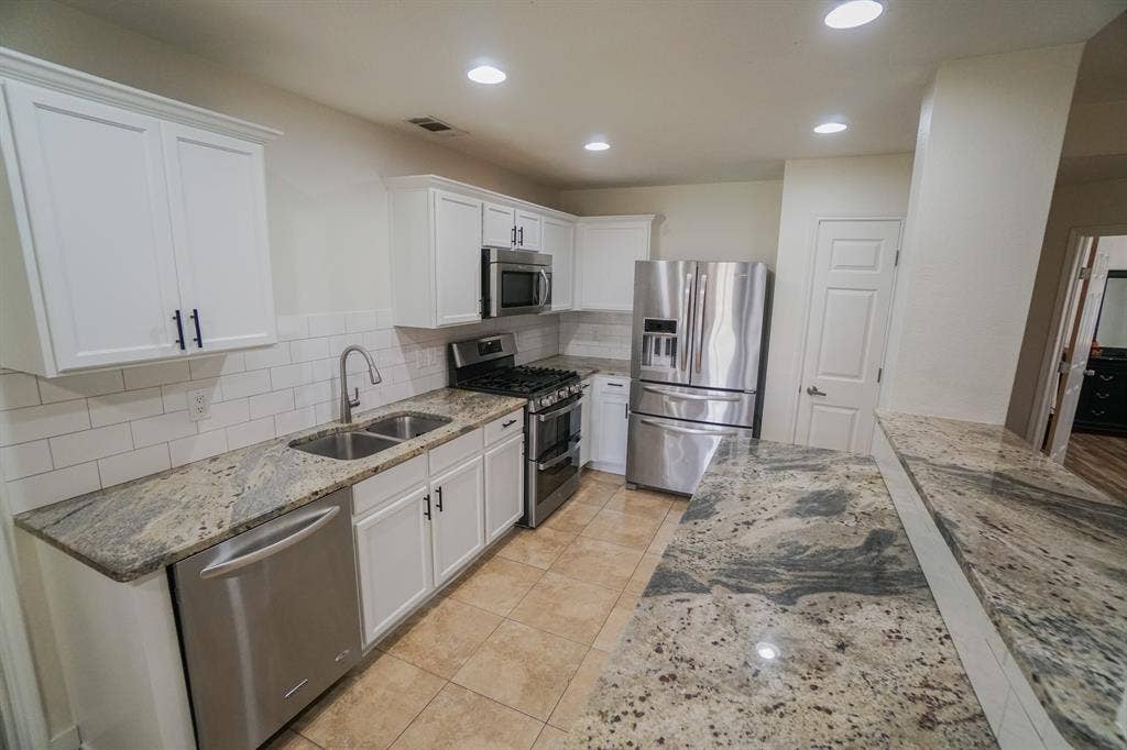 203 Grassy Creek Drive, Wylie, TX 75098 Kitchen featuring white cabinetry with dark hardware, a subway tile backsplash, stainless steel appliances, and granite countertops