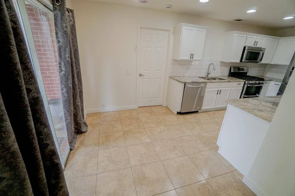 203 Grassy Creek Drive, Wylie, TX 75098 Kitchen featuring white cabinetry, light granite countertops, a subway tile backsplash, stainless steel appliances, and tile flooring