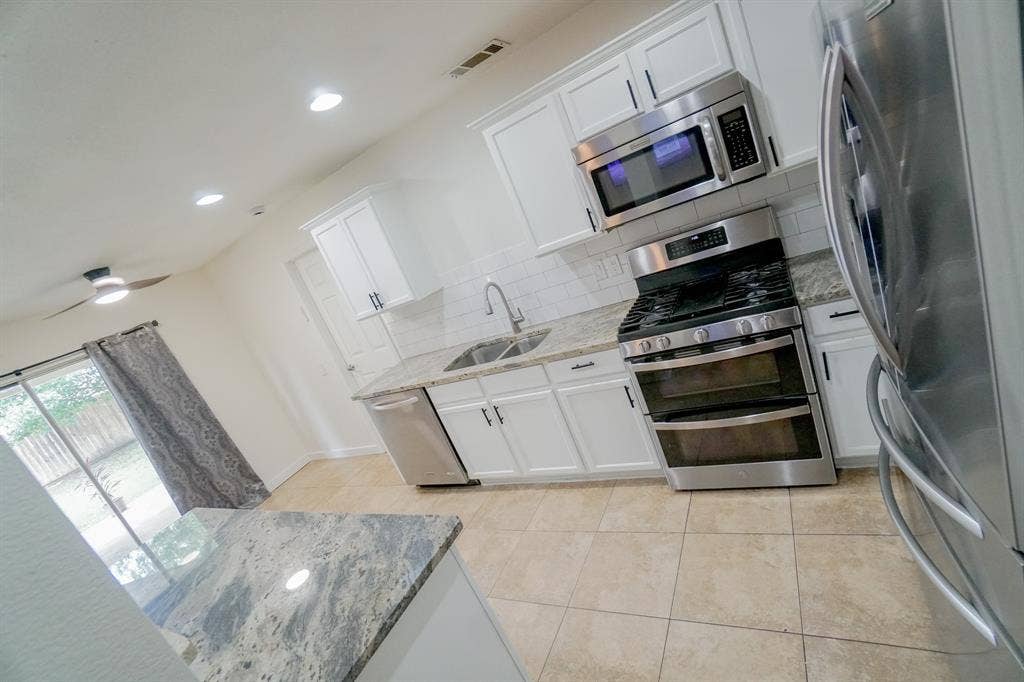 203 Grassy Creek Drive, Wylie, TX 75098 Contemporary kitchen featuring white cabinetry, stone countertops, stainless steel appliances, a subway tile backsplash, and ceramic tile flooring