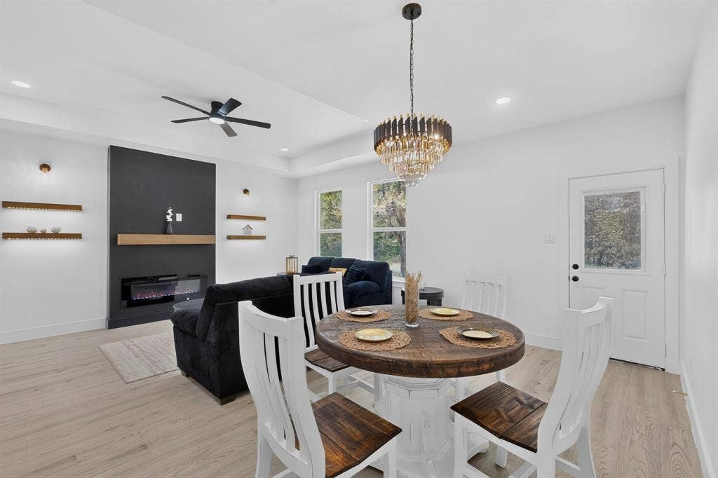 343 SCHOONER Road, Gun Barrel City, TX 75156 Open-concept living space featuring wood-finish flooring, a modern electric fireplace with a dark accent wall and light wood mantel, and illuminated floating shelves