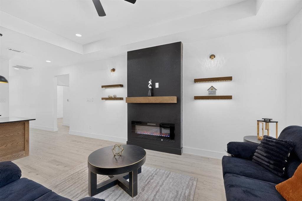 343 SCHOONER Road, Gun Barrel City, TX 75156 Modern living area featuring a fireplace with a black surround and wood mantel, recessed lighting, wood-finish flooring, and tray ceiling details