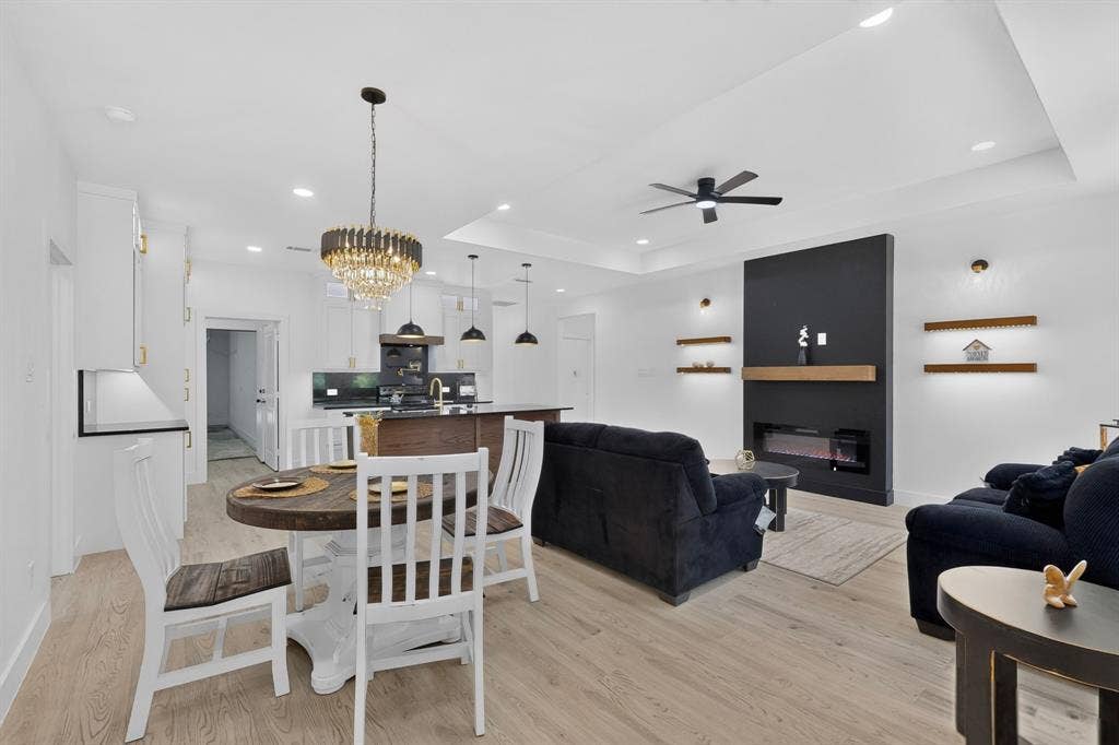 343 SCHOONER Road, Gun Barrel City, TX 75156 Open-concept living space featuring wood-finish flooring throughout, a modern fireplace with a dark accent wall and wood mantel, and tray ceilings