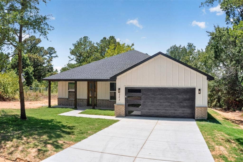 343 SCHOONER Road, Gun Barrel City, TX 75156 Contemporary exterior featuring light vertical siding, a dark asphalt shingle roof, and a modern garage door with frosted glass panels