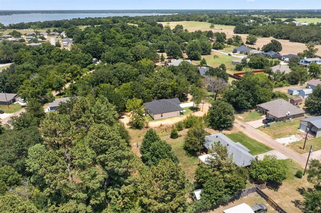 343 SCHOONER Road, Gun Barrel City, TX 75156 Aerial perspective showcasing a residential area bordered by a large body of water, extensive tree coverage, and open fields
