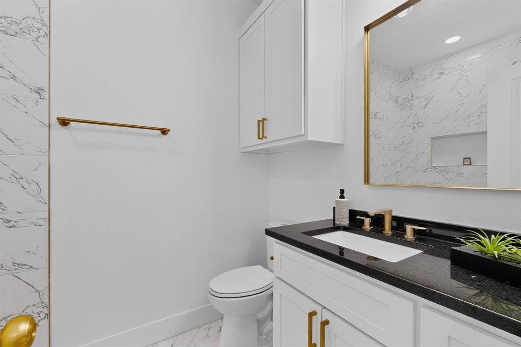 343 SCHOONER Road, Gun Barrel City, TX 75156 White vanity with a black countertop, gold-tone hardware, and a framed mirror