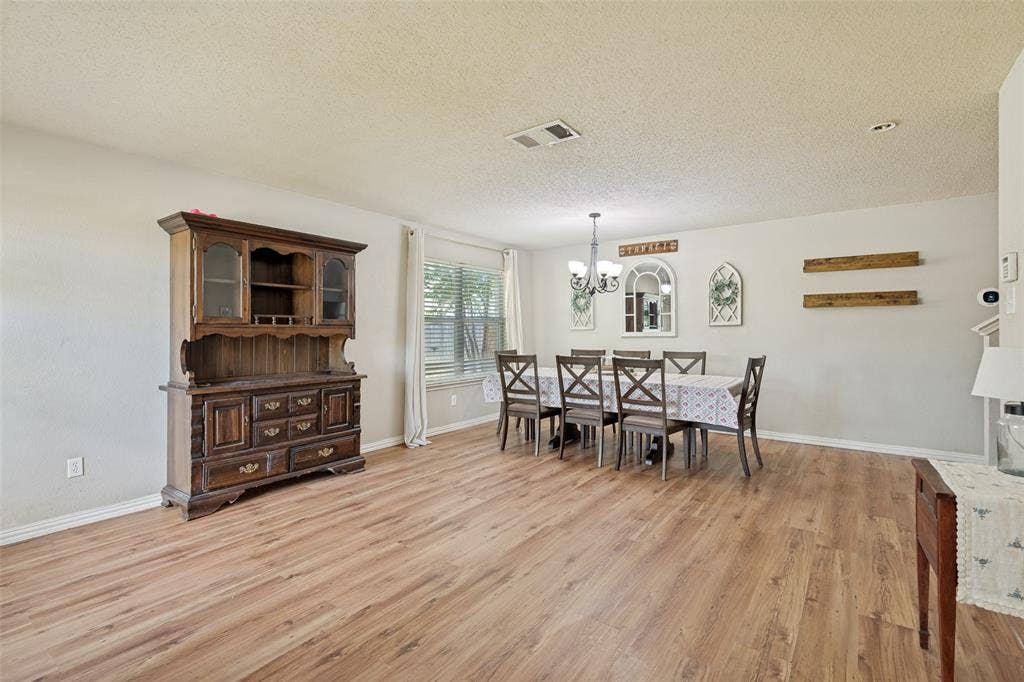 605 Rock Brook Drive, Forney, TX 75126 Spacious room featuring wood-finish flooring, a contemporary chandelier, large window with blinds, and white baseboards