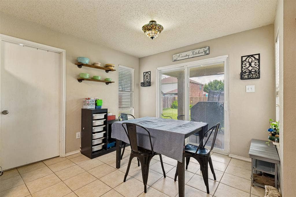 605 Rock Brook Drive, Forney, TX 75126 Bright dining area featuring tile flooring, sliding glass doors, built-in shelving, a ceiling-mounted light fixture, and neutral wall tones