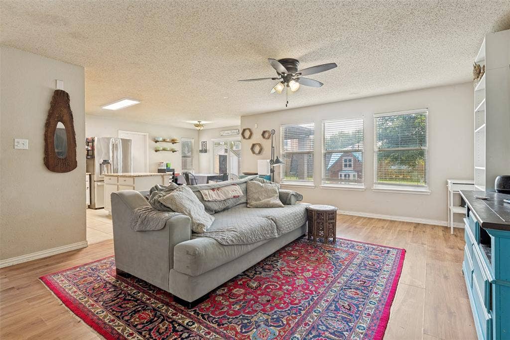 605 Rock Brook Drive, Forney, TX 75126 Open-concept living area featuring wood-finish flooring, multiple windows providing ample natural light, a ceiling fan with integrated lighting, and recessed ceiling lighting