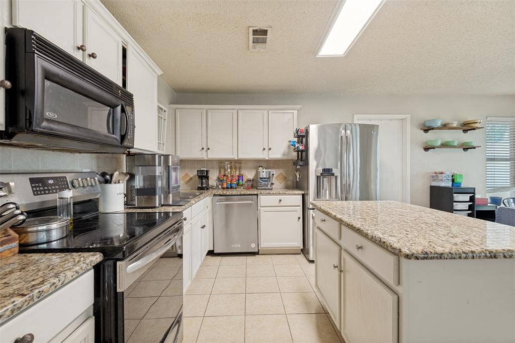 605 Rock Brook Drive, Forney, TX 75126 Kitchen featuring an expansive center island with a light granite-finish countertop