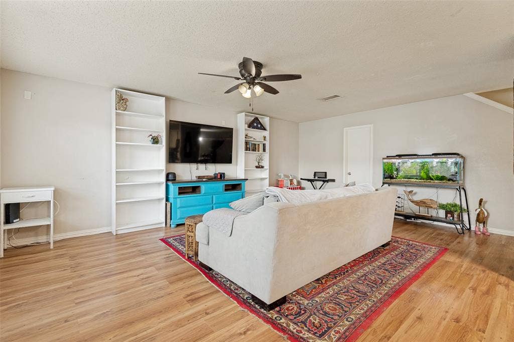 605 Rock Brook Drive, Forney, TX 75126 Living area featuring wood-finish flooring, light neutral wall paint, and a ceiling fan with integrated lighting