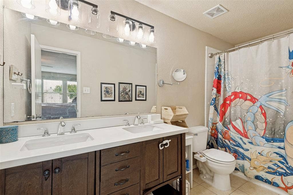 605 Rock Brook Drive, Forney, TX 75126 Dual vanity with white undermount sinks, chrome fixtures, and a spacious framed mirror