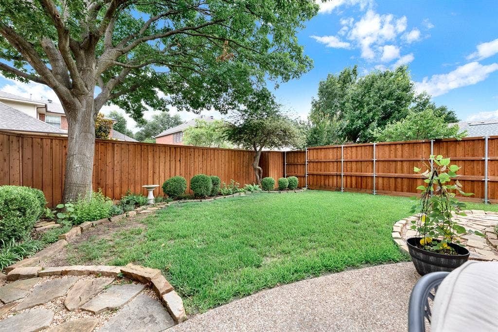 3708 Stockport Drive, Plano, TX 75025 The deeply stained privacy fence wraps around a beautifully manicured lawn, creating a secure, hidden oasis framed by neatly edged stone borders. Imagine playing a game of catch with family or watching a pet run freely on a sunny afternoon.