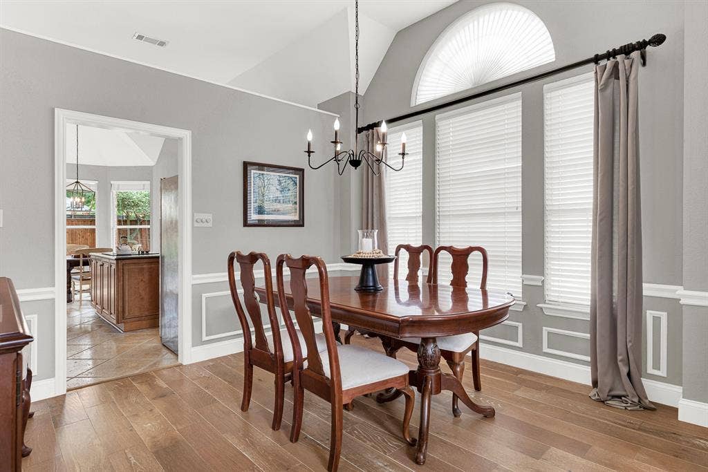 3708 Stockport Drive, Plano, TX 75025 Vaulted ceilings rise dramatically above picture-frame wainscoting, while a tall arched transom window draws natural light deep into the space from two directions. This room was made for a proper dinner party — the kind where nobody checks their phone