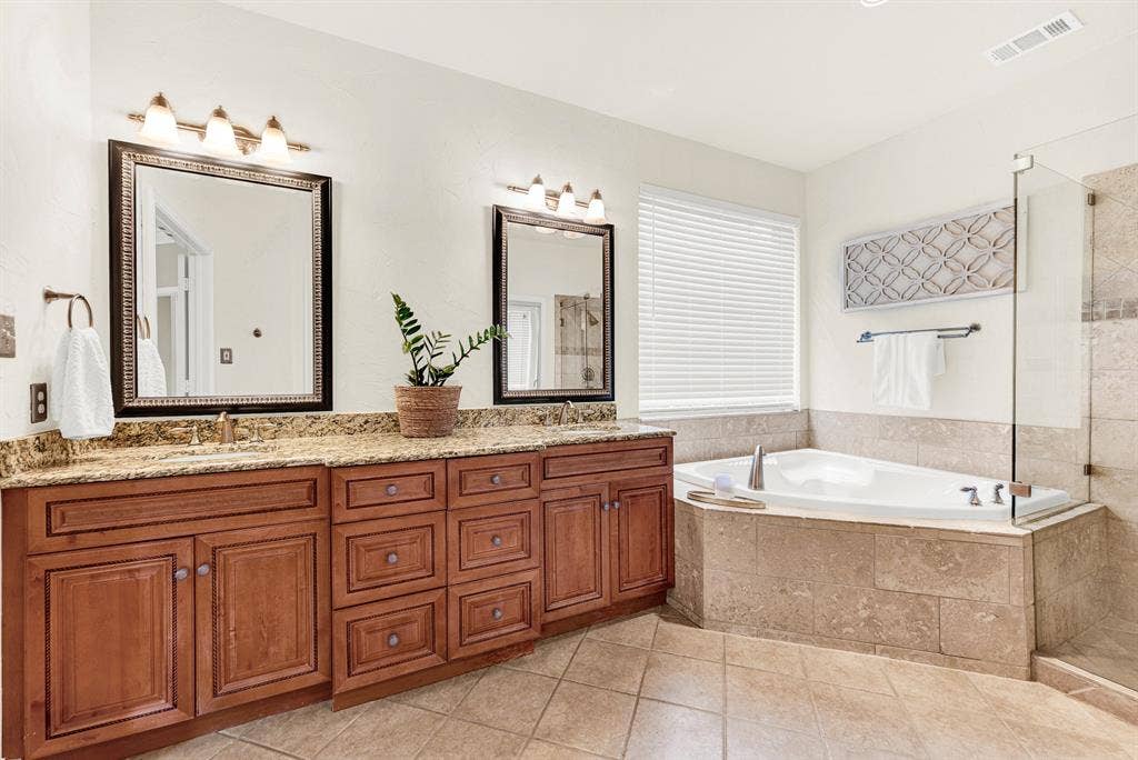 3708 Stockport Drive, Plano, TX 75025 An oversized soaking tub serves as the room's central retreat, tucked beneath a wide window. Sink into a warm evening bath to wash away the day.