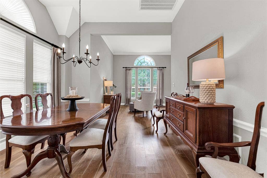 3708 Stockport Drive, Plano, TX 75025 The vaulted ceiling peaks at the far end where an arched window frames a green view, creating a natural focal point that makes the long, gracious room feel both grand and intimate. Afternoon light moves slowly across these hardwood floors all day long — it's the kind of thing you notice and love.
