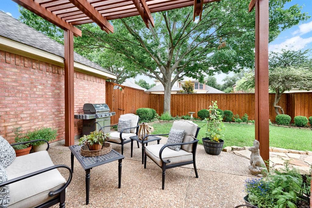 3708 Stockport Drive, Plano, TX 75025 A substantial wooden pergola filters the afternoon sun, casting geometric shadows across the textured aggregate patio. Enjoy a quiet weekend afternoon listening to the rustle of leaves from the mature shade tree just beyond the patio edge.