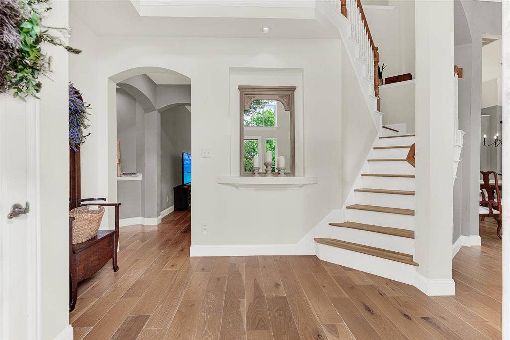 3708 Stockport Drive, Plano, TX 75025 A charming built-in display niche with decorative molding is framed by the graceful curve of the staircase on one side and an arched passageway on the other, creating a foyer that feels both intimate and architecturally layered. Coming home feels different when the entry itself is this considered and calm.