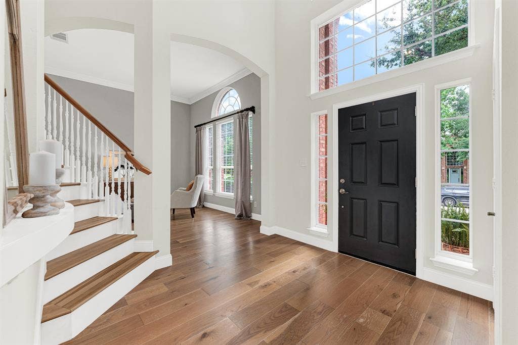 3708 Stockport Drive, Plano, TX 75025 A soaring two-story window wall beside the black front door floods the entry with natural light, while wide-plank hardwood floors and a sweeping staircase set an immediately warm and welcoming tone. Every single person who walks through that door stops for just a moment — this entry earns it