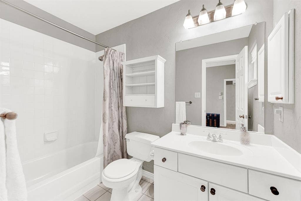 3708 Stockport Drive, Plano, TX 75025 Crisp white tile and cabinetry bounce the vanity light, maximizing the bright and airy feel of this private bath. Visitors can comfortably unpack their essentials and enjoy a refreshing, hassle-free morning routine.