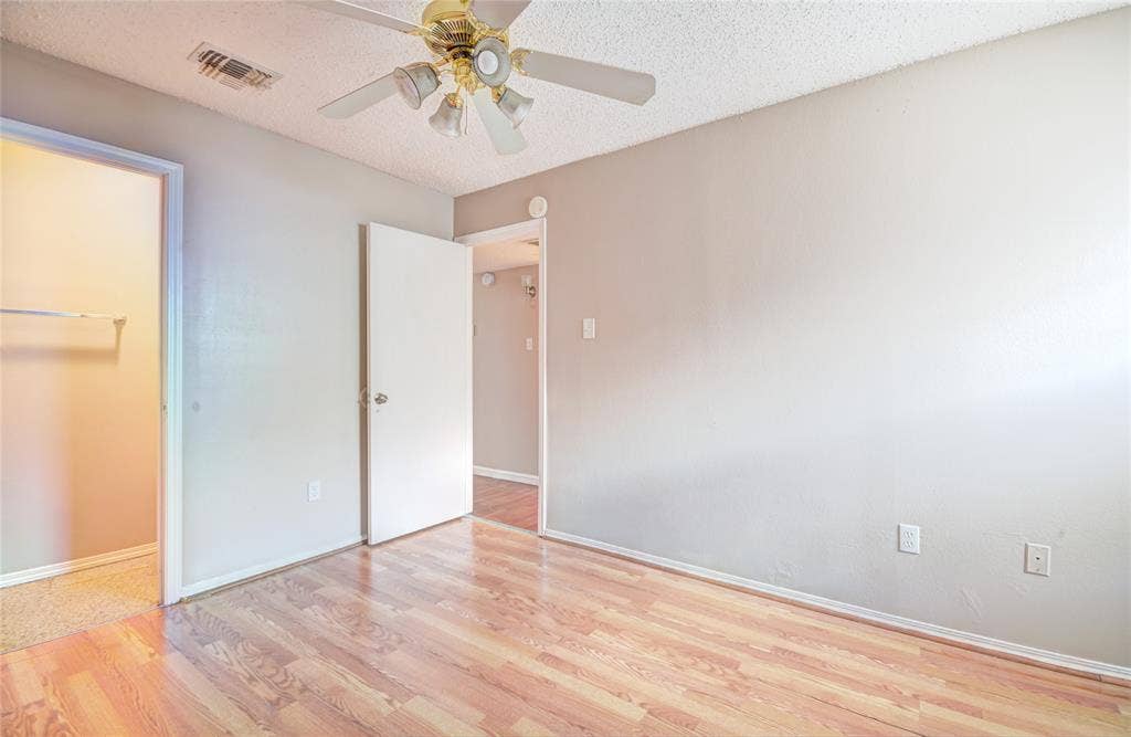 1912 Bernice Street, #B, Haltom City, TX 76117 Primary bedroom featuring luxury plank flooring, half bath, light neutral wall tones, and a ceiling fan with integrated lighting