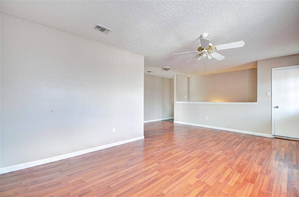 1912 Bernice Street, #B, Haltom City, TX 76117 Spacious interior living area featuring luxury plank flooring, light neutral wall tones, and a ceiling fan with integrated lighting