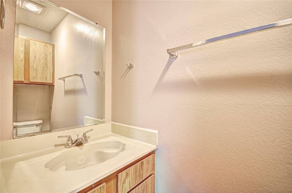 1912 Bernice Street, #B, Haltom City, TX 76117 Half bathroom includes vanity with an integrated white sink and chrome faucet, set against a full-width mirror