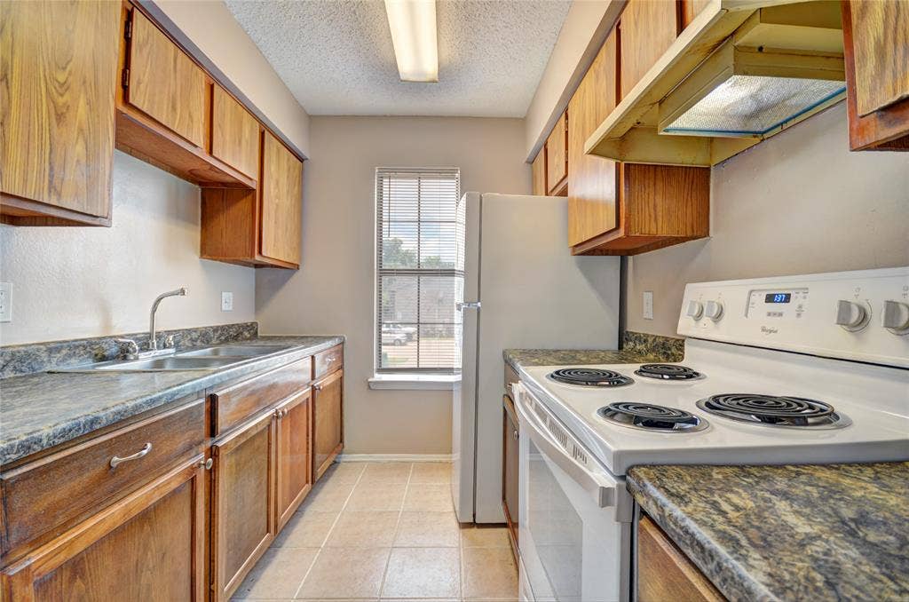 1912 Bernice Street, #B, Haltom City, TX 76117 Kitchen featuring wood-finish cabinetry, upgraded countertops, and tile flooring