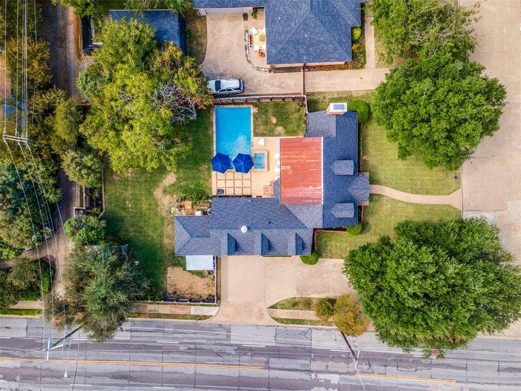 Aerial perspective of a property featuring an in-ground swimming pool, a dedicated spa, a paved patio area, and mature trees on the lot