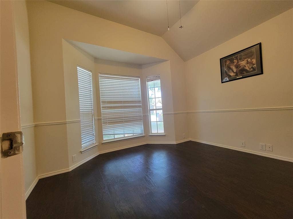 Office with bay window, glass door, and dark wood-style floors, ceiling fan, and lofted ceiling