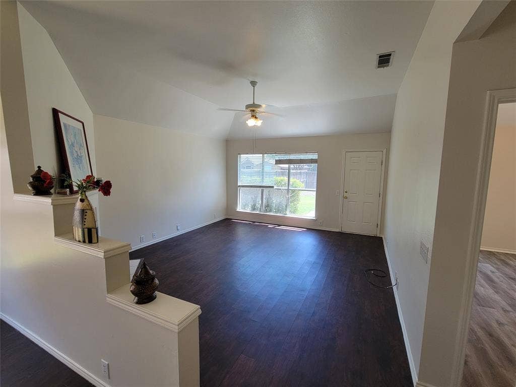 Living room with a fireplace, dark wood-style floors, ceiling fan, and lofted ceiling