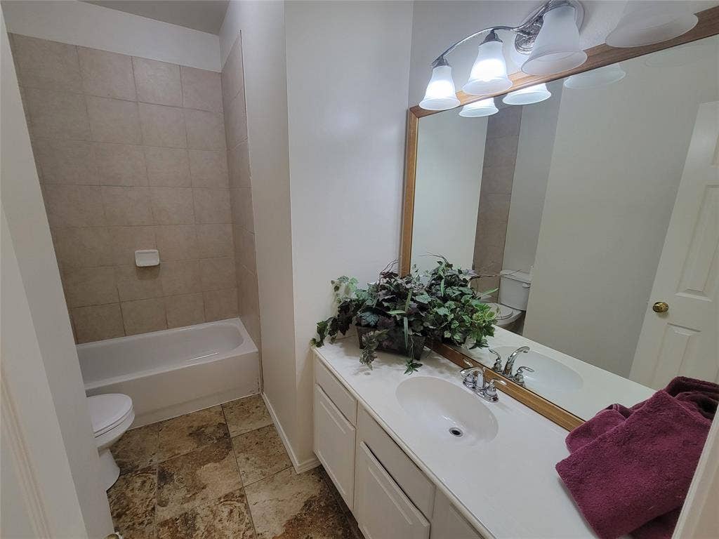 Full bathroom with vanity, tiled shower / bath, toilet, and tile flooring