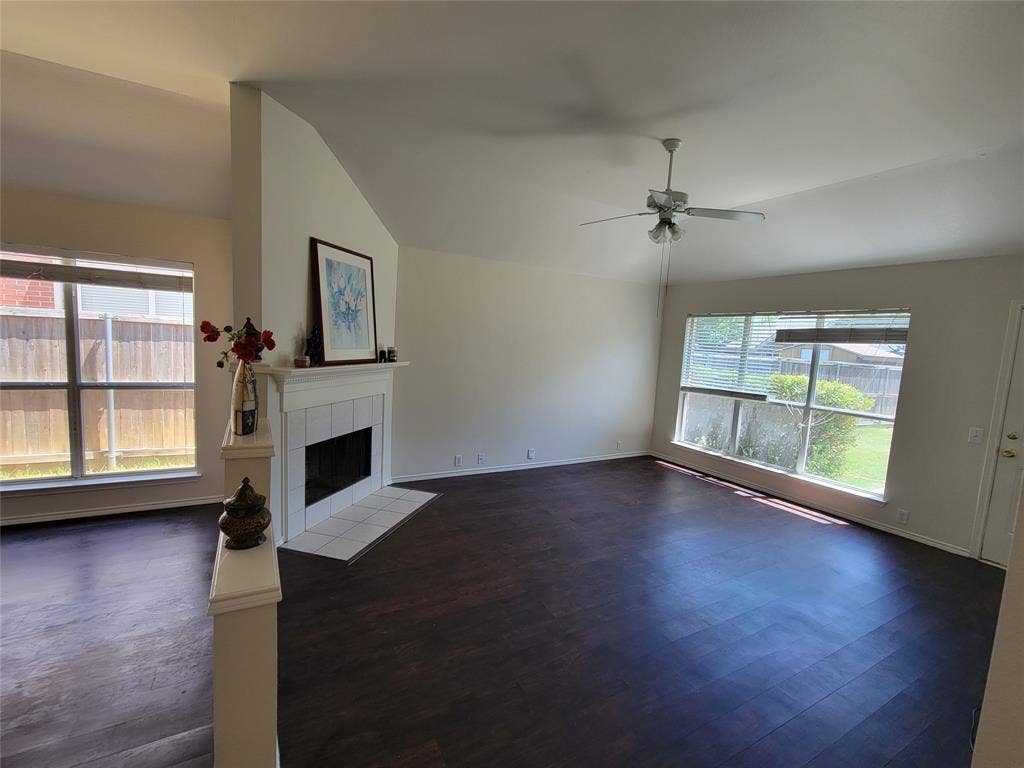 Living room with a fireplace, dark wood-style floors, ceiling fan, and lofted ceiling