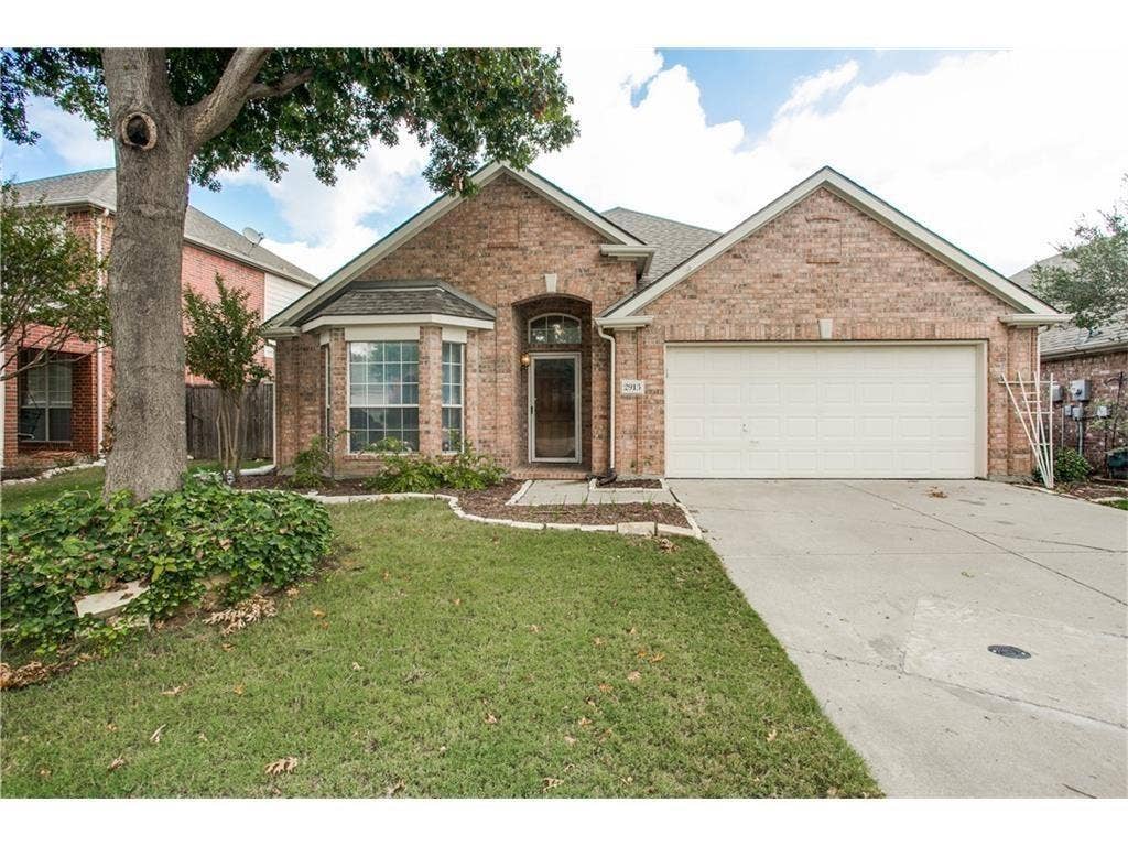 Front of home with front entry garage and large tree