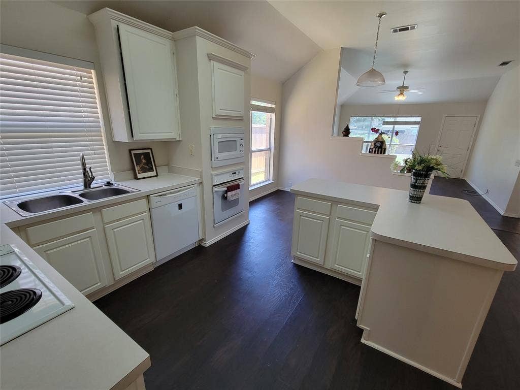 Kitchen with ceiling fan, white appliances, sink, vaulted ceiling, and dark wood-style floors